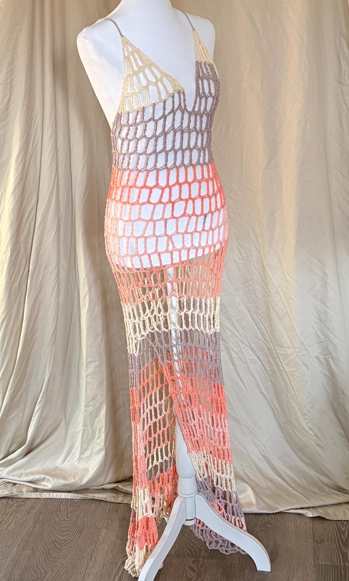 Multicolored crochet dress on a mannequin against a beige curtain background