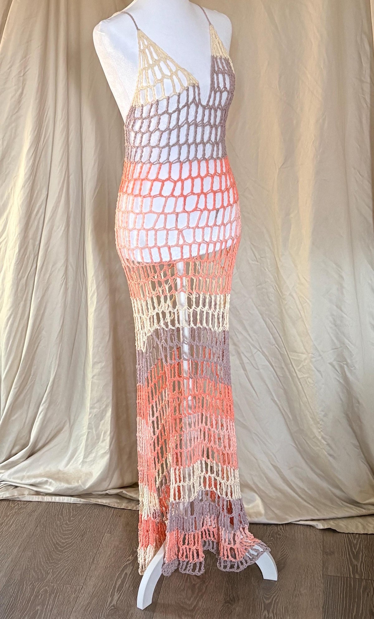 Mannequin wearing a colorful crochet dress against a plain background