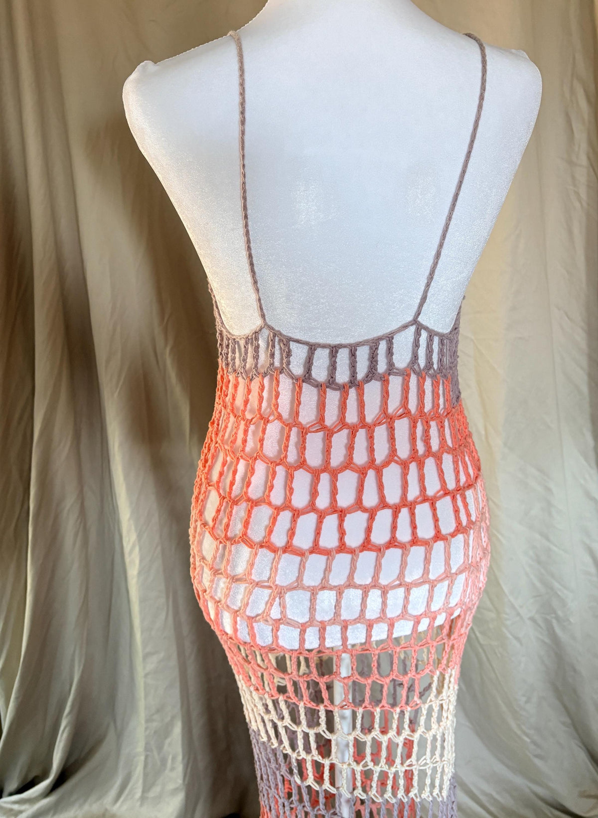 Back of a colorful beach dress in a mannequin in front of a beige background