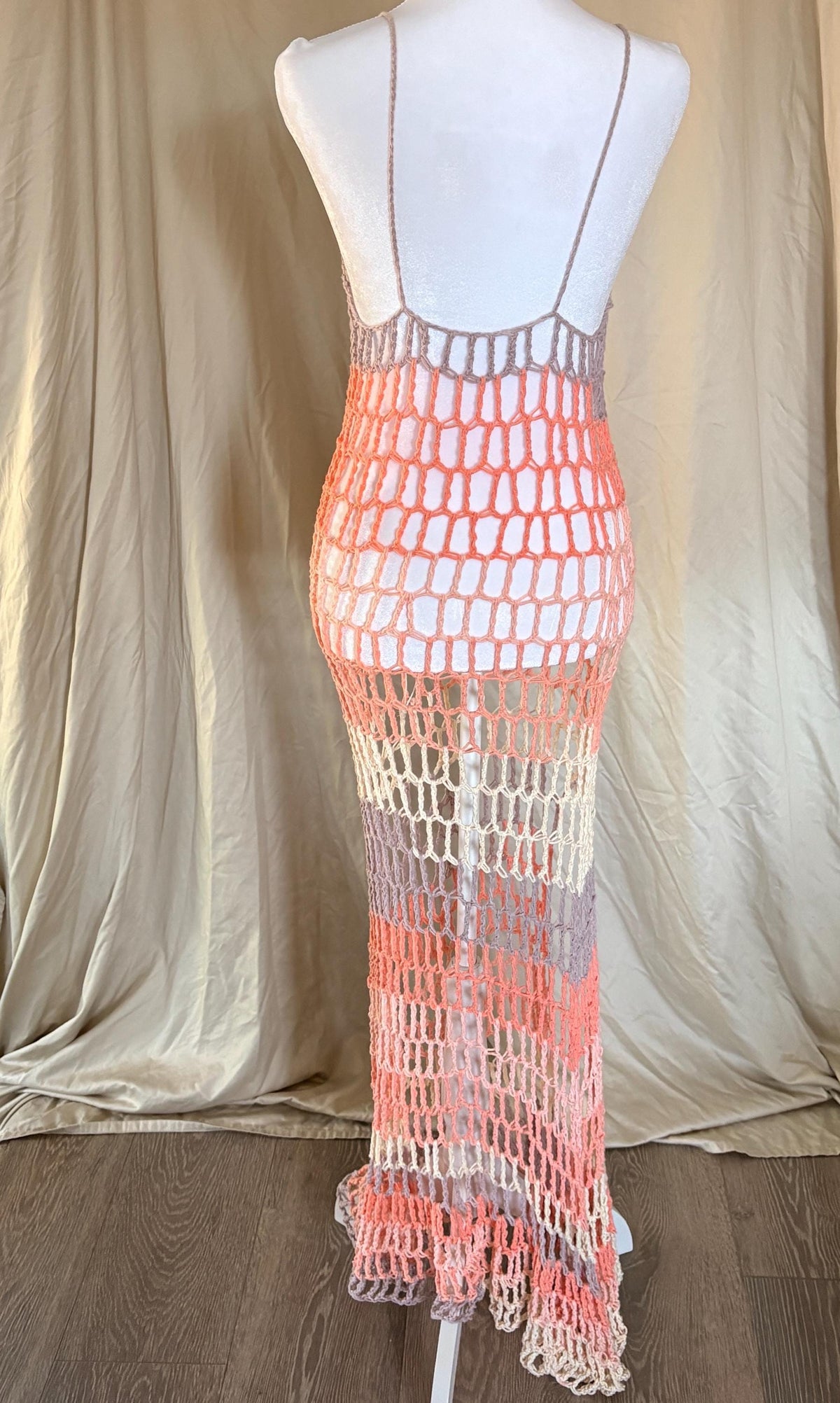 Mannequin wearing a crochet dress with a gradient color pattern against a neutral background.